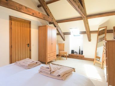 A bedroom with wooden beams a wardrobe a chair and a mirror at The Warren in Bamburgh