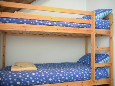 A wooden bunk bed with blue polka dot bedding and a folded towel on the lower bed at The Warren in Bamburgh