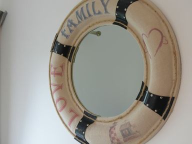 A wall mirror with a frame shaped like a life buoy with the words family and love on it