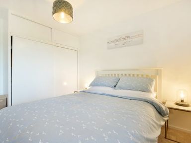 A bedroom with a double bed with blue patterned bedding and bedside tables with lamps at Coastal Plaice in Beadnell