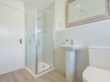 A bathroom with a glass shower enclosure a pedestal sink and a toilet at Coastal Plaice Beadnell