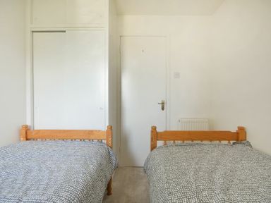 A bedroom with two single beds with wooden frames and patterned bedspreads at Coastal Plaice in Beadnell