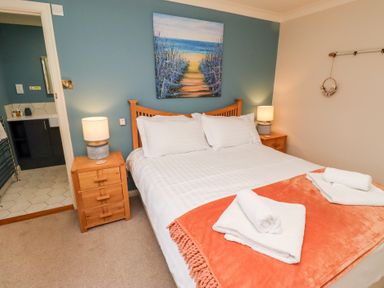 A bedroom with a double bed and orange blanket with towels on at The Wynd in Bamburgh