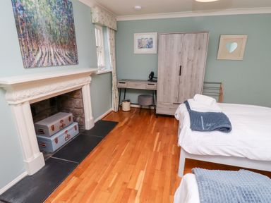 A bedroom with two beds and a fireplace with suitcases inside at The Wynd in Bamburgh
