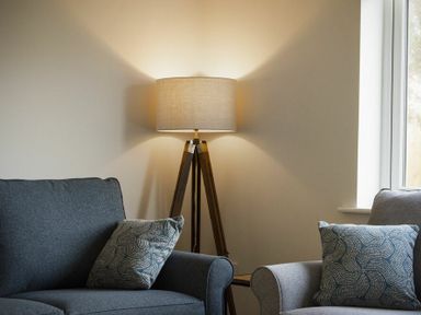 A living room with two armchairs a floor lamp and a window at Luna Tide in Seahouses