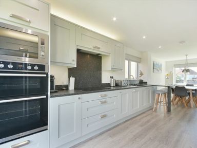 A kitchen with white cabinets black countertops and built in oven at Luna Tide in Seahouses