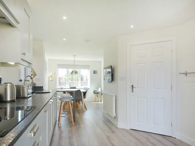 A kitchen with countertop appliances stools and a dining table with chairs near a window at Luna Tide in Seahouses