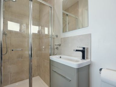 A bathroom with tiled shower enclosure a sink with faucet and a mirror at Luna Tide in Seahouses