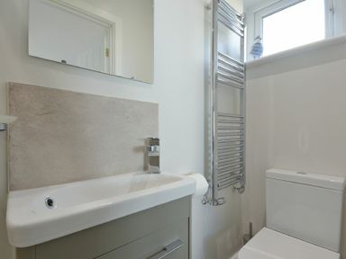 A bathroom with a sink cabinet mirror toilet and towel radiator at Luna Tide in Seahouses