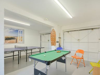 A game room with a pool table a ping pong table and colorful folding chairs at Luna Tide in Seahouses