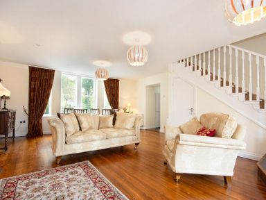 A living room with couches a rug wooden floor and stairs at The Old Concert Room in Alnmouth