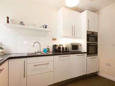 A kitchen with white cabinets a sink microwave toaster and oven at The Old Concert Room in Alnmouth