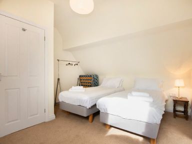 A bedroom with two single beds side by side and a bedside table with a lamp at The Old Concert Room in Alnmouth