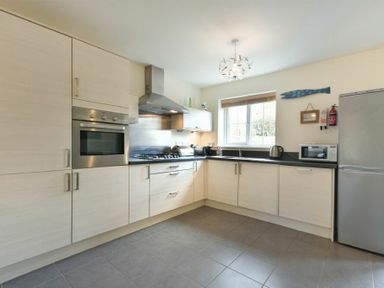 A kitchen with built in oven stove refrigerator microwave kettle and cupboards at Coast View in Beadnell