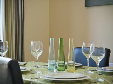 A dining table set with plates wine glasses and three tall narrow vases at Coast View in Beadnell