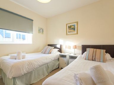 A bedroom with two single beds a nightstand and lamps at Coast View in Beadnell