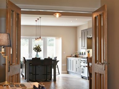 A kitchen with a central island with chairs pendant lights and cabinetry at Bradacar in Seahouses