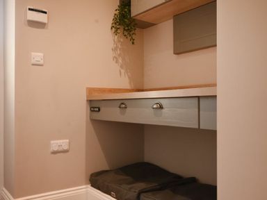 A small nook with a wooden countertop, grey drawers, wall-mounted cabinets, and cushions below the counter at Bradacar in Seahouses