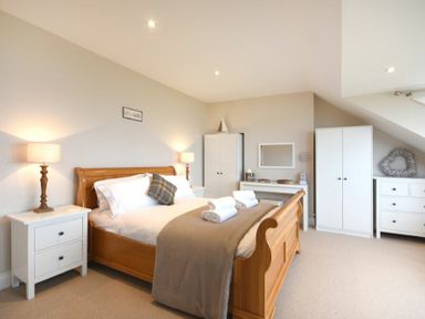 A bedroom with a wooden bed and white bedside tables with lamps at Bradacar in Seahouses