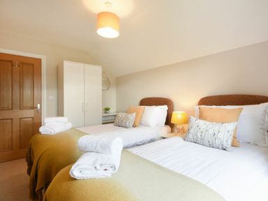 A bedroom with two single beds each with cushions and towels a wardrobe and a wooden door at Bradacar in Seahouses