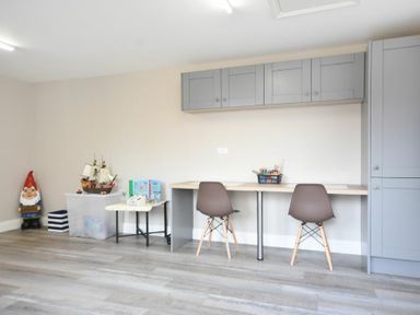 A room with two chairs at a desk with gray cabinets above and toys including a gnome and a ship model on the side at Bradacar in Seahouses