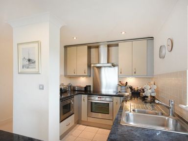 A kitchen with beige cabinets stainless steel oven and hood a sink and countertop utensils at Castle View at the Viking Seahouses
