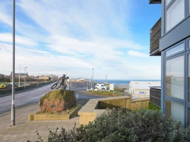A street view with a statue on a rock near a building overlooking the sea at Castle View at the Viking in Seahouses