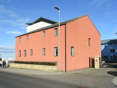 A pink two-story building with multiple small windows and a street lamp in front at Castle View at the Viking in Seahouses