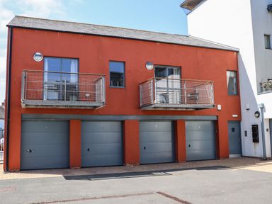 A building with four blue garage doors and two metal balconies above at Castle View at the Viking in Seahouses