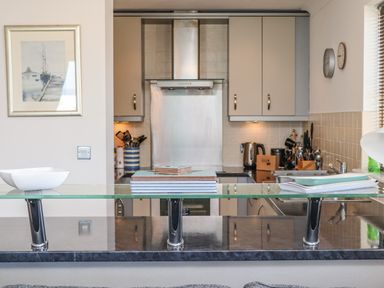 A kitchen with cabinets a stove a kettle and cooking utensils at Castle View at the Viking in Seahouses