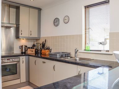 A kitchen with cabinets a sink a stove a kettle and utensils on the counter at Castle View at the Viking in Seahouses