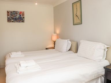 A bedroom with two single beds bedside table and lamp and framed pictures on walls at Castle View at the Viking in Seahouses