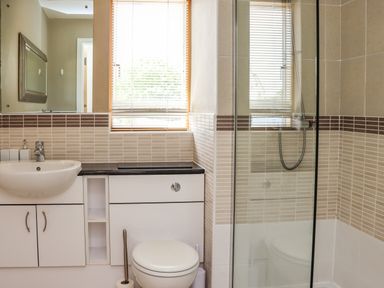 A bathroom with a sink cabinet toilet and glass-enclosed shower at Castle View at the Viking in Seahouses