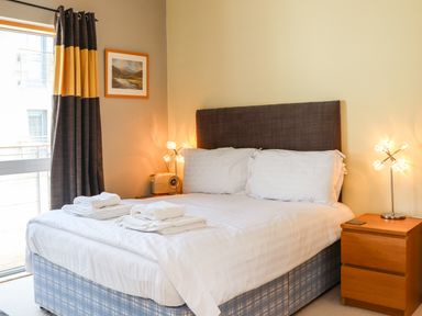 A bedroom with a bed towels on it beside a window with curtains at Castle View at the Viking in Seahouses
