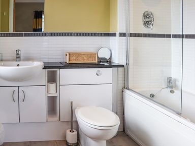 A bathroom with a toilet sink countertop bathtub and mirror at Castle View at the Viking in Seahouses