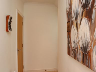 A hallway with a wooden door and two abstract paintings on the walls at Castle View at the Viking in Seahouses