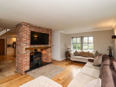 A living room with two sofas a brick fireplace and a mounted TV at The Old Stables in Bamburgh