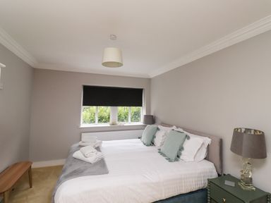 A bedroom with a bed with pillows and towels a bench by the wall and a nightstand with a lamp at The Old Stables Bamburgh