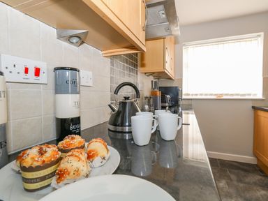 A kitchen countertop with pastries cups a kettle and canisters at Cove Street Cottage in Weymouth