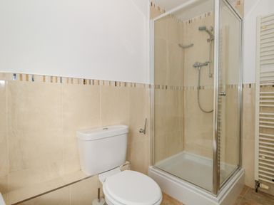 A bathroom with a toilet and a glass-enclosed shower at Cove Street Cottage in Weymouth