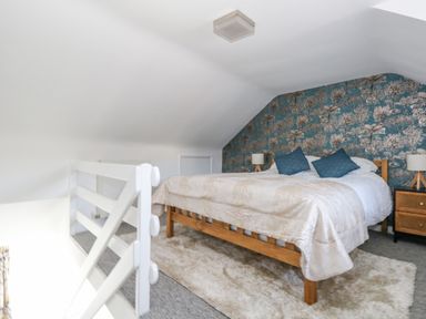 A bedroom with a wooden bed blue pillows and floral wallpaper at Cove Street Cottage in Weymouth