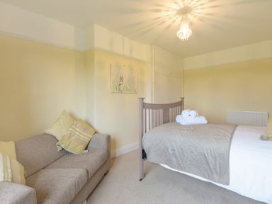 A bedroom with a bed with folded towels on it and a sofa with cushions at Dairyman's Cottage in Amble
