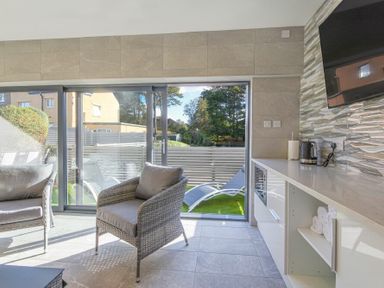 A sitting area with wicker chairs and sliding glass doors opening to an outdoor space at Riverview Alnmouth