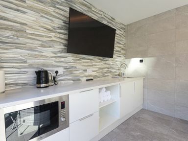 A kitchenette with a microwave oven electric kettle sink and wall-mounted TV at Riverview Alnmouth