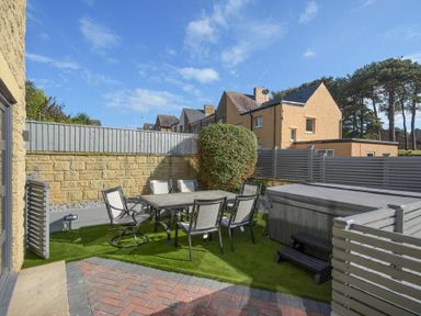 A backyard patio with outdoor dining table and chairs and a covered hot tub at Riverview Alnmouth