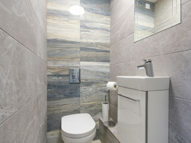 A small bathroom with a toilet sink mirror and tiled walls at Riverview Alnmouth
