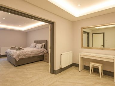 A bedroom with a double bed and towels and a dressing table with a mirror at Riverview Alnmouth