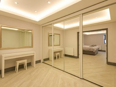 A dressing room with a white vanity table and stool with mirrored sliding closet doors at Riverview Alnmouth