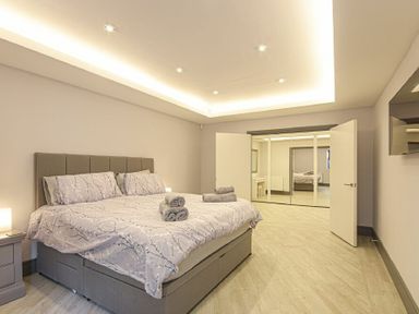 A bedroom with a bed a bedside table and open doors leading to a mirrored wardrobe at Riverview Alnmouth