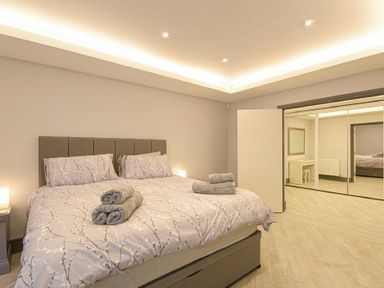A bedroom with a bed folded towels bedside tables and a mirrored closet door at Riverview Alnmouth